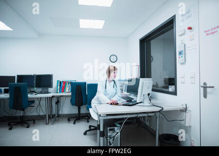Giovani donne medico lavora su computer in ospedale, Freiburg im Breisgau, Baden-Württemberg, Germania Foto Stock