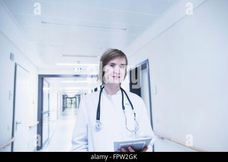 Giovani donne medico negli appunti di contenimento in ospedale corridoio, Freiburg im Breisgau, Baden-Württemberg, Germania Foto Stock