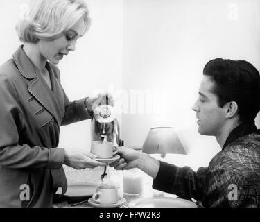 Anni sessanta coppia giovane che indossa vesti avente il caffè del mattino dalla caffettiera elettrica caffettiera Foto Stock