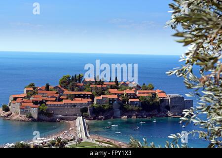 Vista di Sveti Stefan isola attraverso gli olivi dalla strada costiera in Montenegro in un giorno caldo nel settembre 2015 Foto Stock