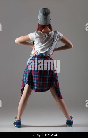 Un attraente montare carino giovane donna indossa casual plaid shirt in piedi con le mani sui fianchi. Stile moderno bellissima ballerina workin Foto Stock