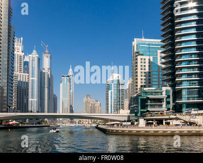 Promenade, highrise waterfront edifici, barche e ponte nel quartiere di Marina di Dubai, Emirati Arabi Uniti Foto Stock