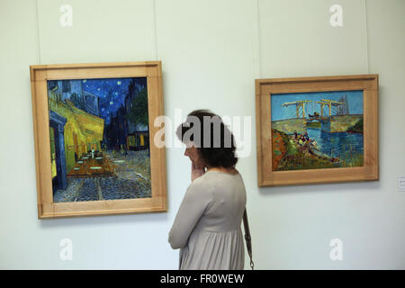 Visitatore guarda i dipinti Cafe terrazza durante la notte (1888) e il Ponte di Langlois ad Arles (1888) di Vincent van Gogh nel Kroller Muller Museum di Otterlo, Paesi Bassi. Foto Stock