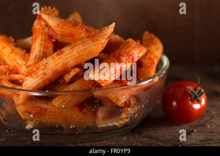 Penne pasta in salsa di pomodoro con carne e i pomodori su un sfondo di legno Foto Stock