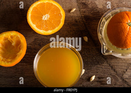 Ciotola del succo d'arancia fresco e centrifuga su sfondo di legno Foto Stock