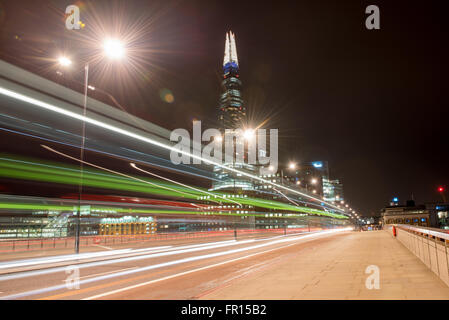 La Shard e Ponte di Londra di notte colorato double decker bus sentieri di luce a Londra, Regno Unito. Foto Stock