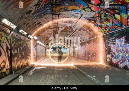 Silhouette di uomo illuminato di filatura filo di lana di notte all'interno del tunnel di graffiti di Waterloo a Londra, Regno Unito Foto Stock