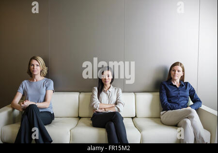 Ritratto di gravi imprenditrici in attesa sul divano Foto Stock