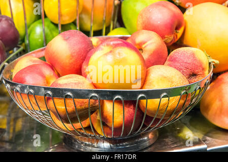 Frutta in metallo ciotola piena di pesche e altri frutti Foto Stock