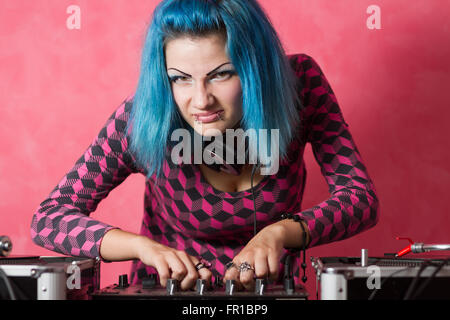 Carino ragazza giovane con tinte blu hari e abito rosa la riproduzione di registrazioni di musica su una attrezzatura professionale Foto Stock