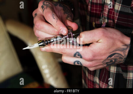 Macchina professionale per la realizzazione di un tatuaggio in pesanti tatuato le mani di un maestro Foto Stock