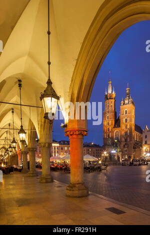 La notte scende sulla piazza del mercato di Cracovia, in Polonia. Guardando dal panno Hall verso la chiesa di Santa Maria. Foto Stock