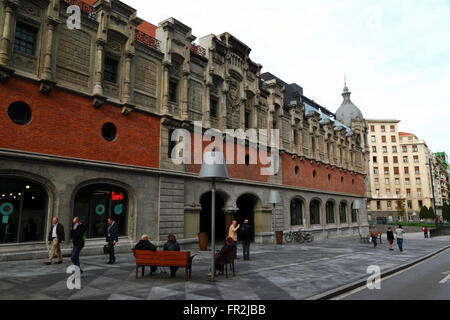 Persone sedute sulla panchina accanto alla parete laterale dell'edificio Alhondiga, ora centro culturale Azkuna Zentroa, Bilbao, Paesi Baschi, Spagna Foto Stock