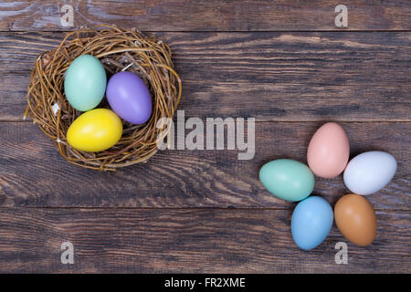 Mazzetto di Pasqua uova colorate nel nido di uccelli su sfondo di legno Foto Stock