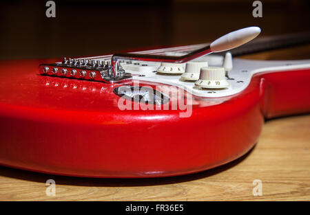 Parte del corpo di rosso stringa 6 chitarra elettrica sdraiato sul pavimento in legno closeup vista posteriore Foto Stock