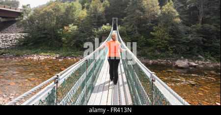 Donna che attraversa grandi Salmon River sul ponte di sospensione in New Brunswick canada Foto Stock