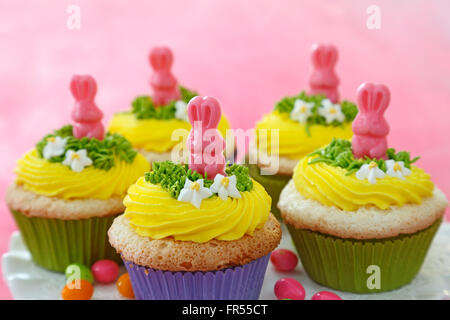 Tortini di Pasqua decorate con conigli di cioccolato e crema di burro giallo. Foto Stock