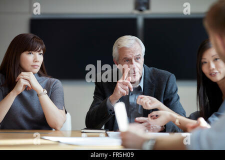 Imprenditore Senior gesticolando e parlando in riunione Foto Stock