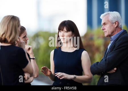 Imprenditrice gesticolando e parlando con i colleghi Foto Stock