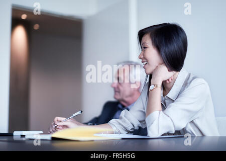 Sorridente imprenditrice prendendo appunti in riunione Foto Stock