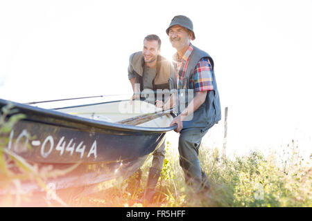 Padre e figlio adulto sollevando la pesca in barca Foto Stock