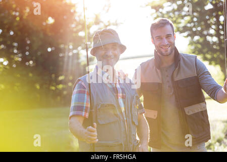 Ritratto sorridente padre e figlio adulto con canne da pesca Foto Stock