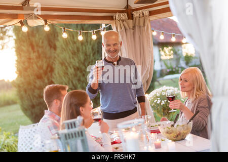 Senior uomo famiglia di tostatura con un bicchiere di vino rosso al patio tabella Foto Stock