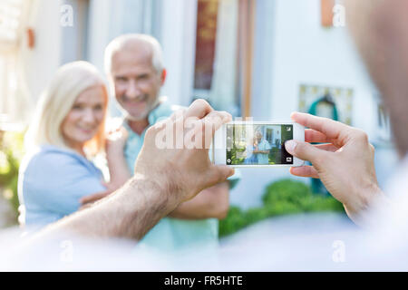 L'uomo fotografare la coppia senior con la fotocamera del telefono Foto Stock