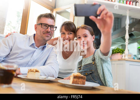 Famiglia con dessert tenendo selfie presso il cafe tabella Foto Stock