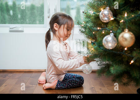 Il Toddler girl decorare albero di Natale Foto Stock
