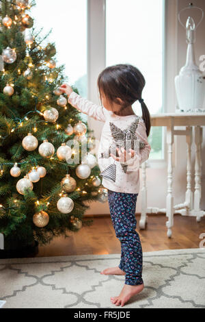 Il Toddler girl decorare albero di Natale Foto Stock