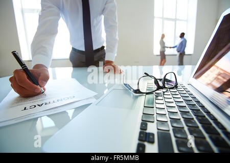 Close-up di un imprenditore tenendo la penna e la firma di documenti Foto Stock