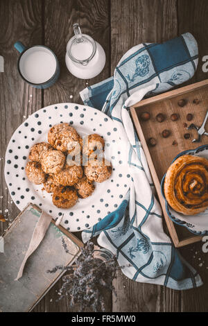 Prenota, lavanda, fiocchi d'avena biscotti e una tazza di latte sul vecchio verticale schede Foto Stock