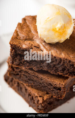 Brownie con gelato su un piatto di portata in ceramica bianca verticale Foto Stock
