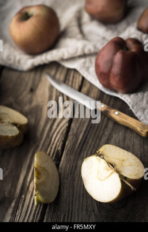 Le mele rosse e le metà di Apple su un tavolo di legno in verticale Foto Stock