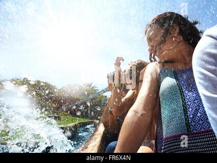 Giovani donne getting spruzzato sul parco acquatico ride Foto Stock
