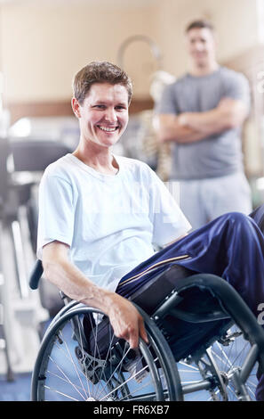 Ritratto uomo sorridente in carrozzella a terapia fisica office Foto Stock