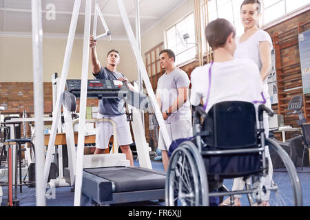 Fisioterapisti la preparazione di tapis roulant per l uomo in sedia a rotelle Foto Stock