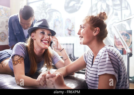 Donna sorridente con amico getting tattoo Foto Stock