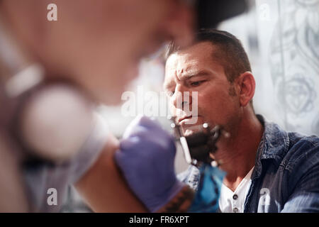 Focalizzato tattoo artist tatuaggio uomo del braccio Foto Stock