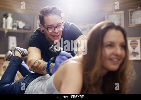 Tattoo Artist tatuaggio donna di back Foto Stock