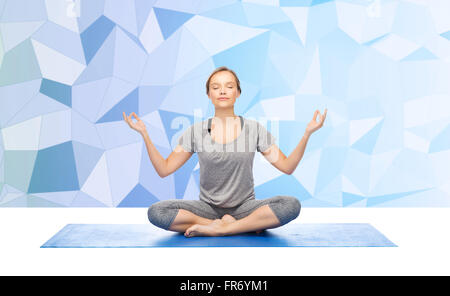 Donna fare meditazione yoga in lotus pone sul tappeto Foto Stock