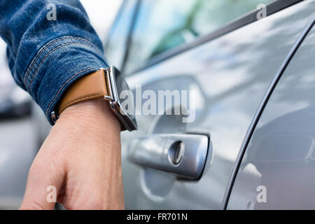 La donna apre la porta della sua vettura con un orologio da polso Foto Stock