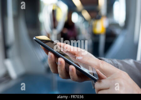 Femmina con il suo smart-phone in metropolitana. Metro. Sms, messaggio, app Foto Stock