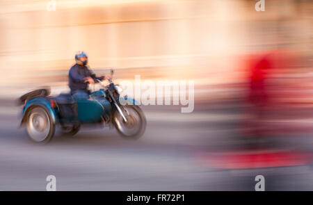 Moto e motocicli sidecar accelerando lungo la strada a El Malecon, Havana, Cuba, West Indies, dei Caraibi e America centrale Foto Stock