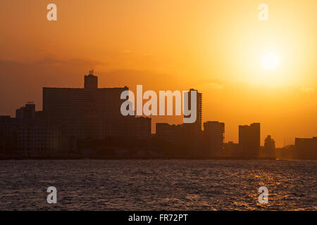 Skyline come il sole tramonta sul mare a El Malecon, Havana, Cuba, West Indies, dei Caraibi e America centrale Foto Stock