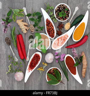 Spezie ed erbe condimento alimentare selezione formanti un abstract su sfondo grigio invecchiato in legno. Foto Stock