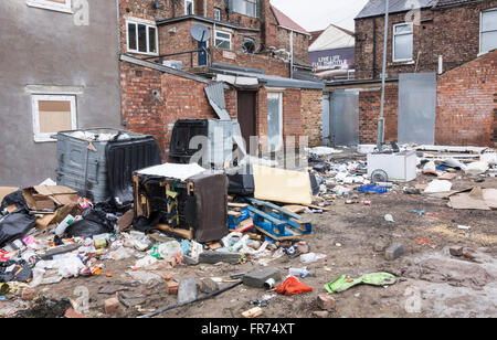 Spazzatura e vecchi mobili oggetto di pratiche di dumping su terreni incolti dietro di case a schiera di essere demolita in Middlesbrough. Regno Unito Foto Stock