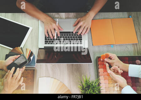 Vista superiore di tre colleghi interior designer discutono dei dati con un nuovo moderno computer laptop e pro tavoletta digitale Foto Stock