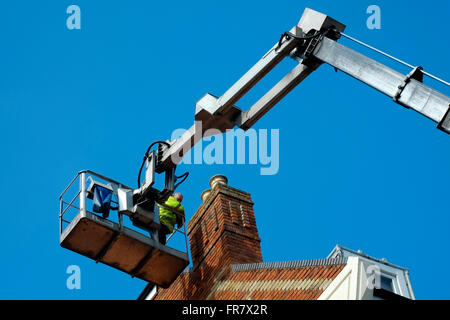 Uomo che lavora in grandi cherry picker sul tetto di casa Inghilterra Regno Unito Foto Stock